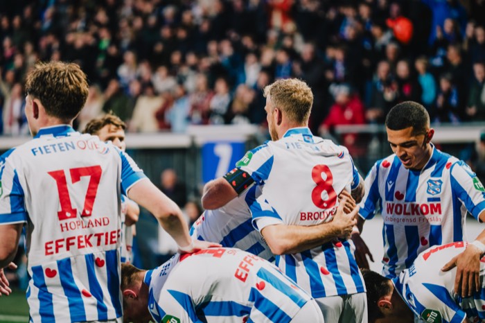 Fußballspieler in blau-weiß gestreiften Trikots umarmen sich jubelnd auf dem Spielfeld eines vollen Stadions bei Flutlicht