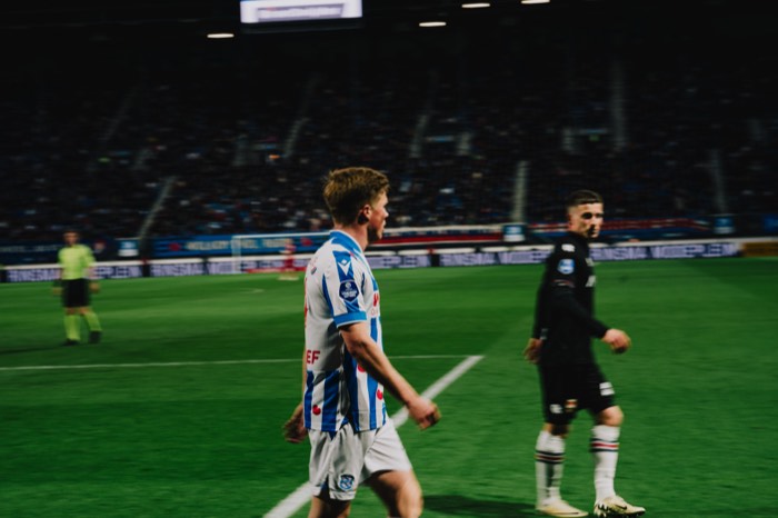 Ein Fußballspieler im gestreiften Trikot läuft unter hellem Flutlicht über den grünen Rasen im nächtlichen Stadion