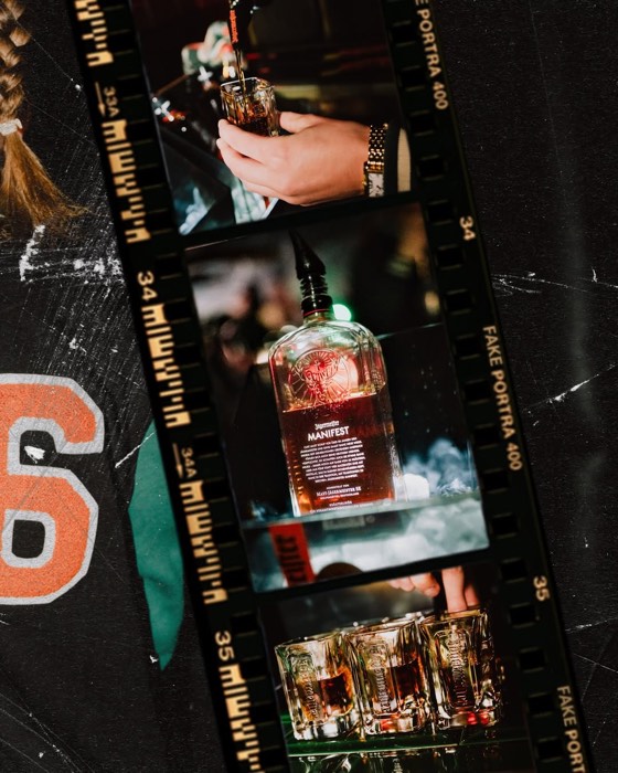 Filmstreifen mit einer beleuchteten Jägermeister Manifest Flasche auf Eis und dem Einschenken von Shots an einer dunklen Bar