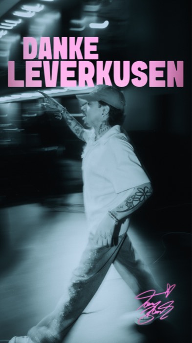 Tony Bauer geht mit zeigender Hand im kühlen Scheinwerferlicht über eine dunkle Bühne unter dem rosa Schriftzug DANKE LEVERKUSEN