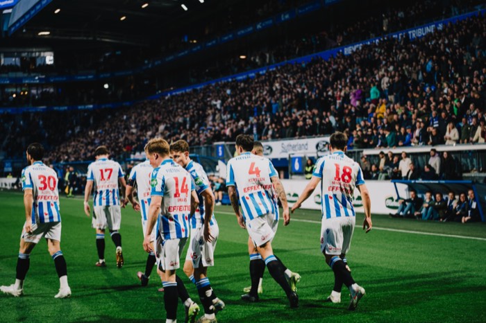 SC Heerenveen Fußballspieler laufen bei hellem Flutlicht vor voll besetzten Tribünen über den grünen Rasen